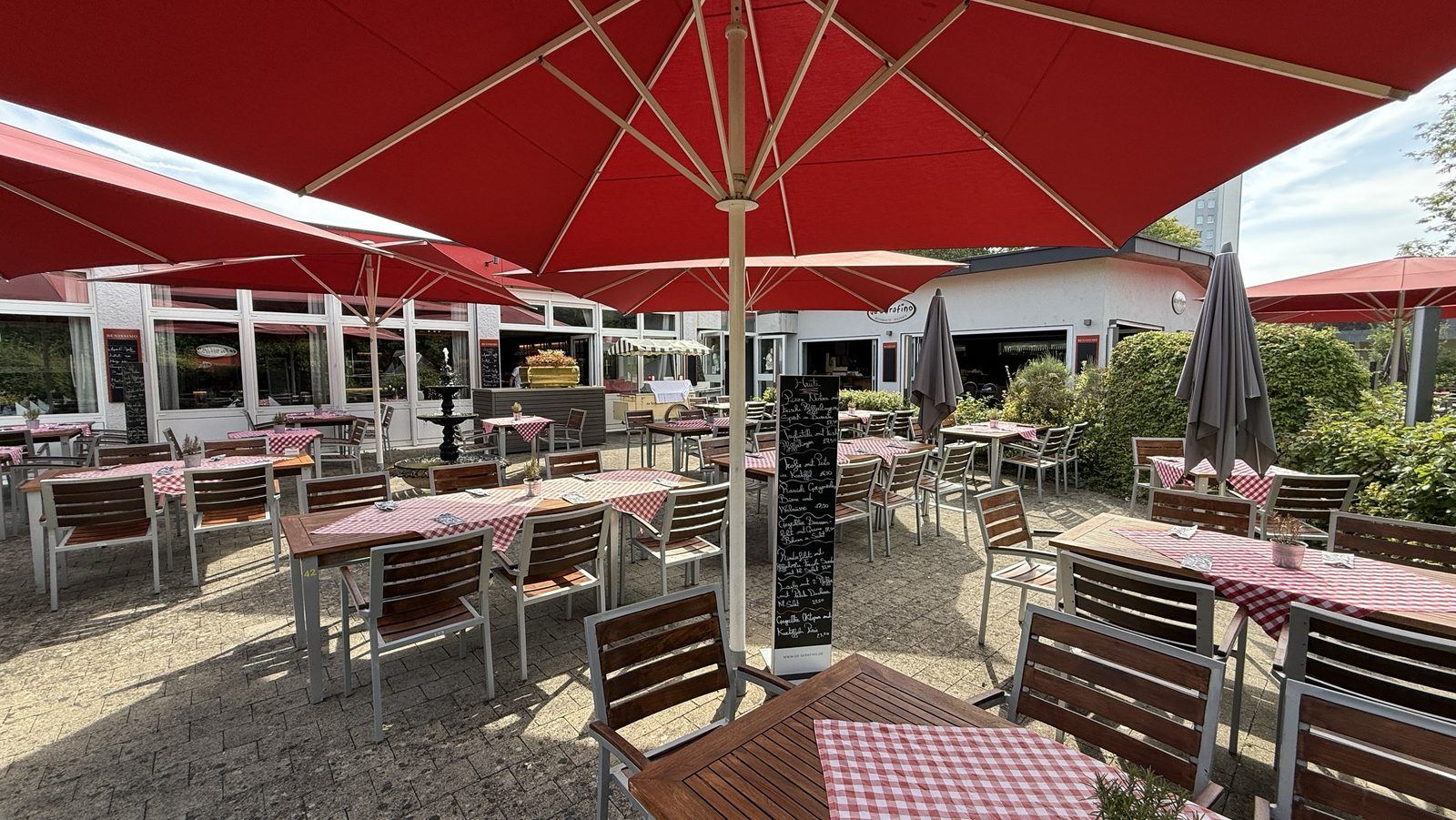 Garten des Ristorante Da Serafino mit roten Sonnenschirmen